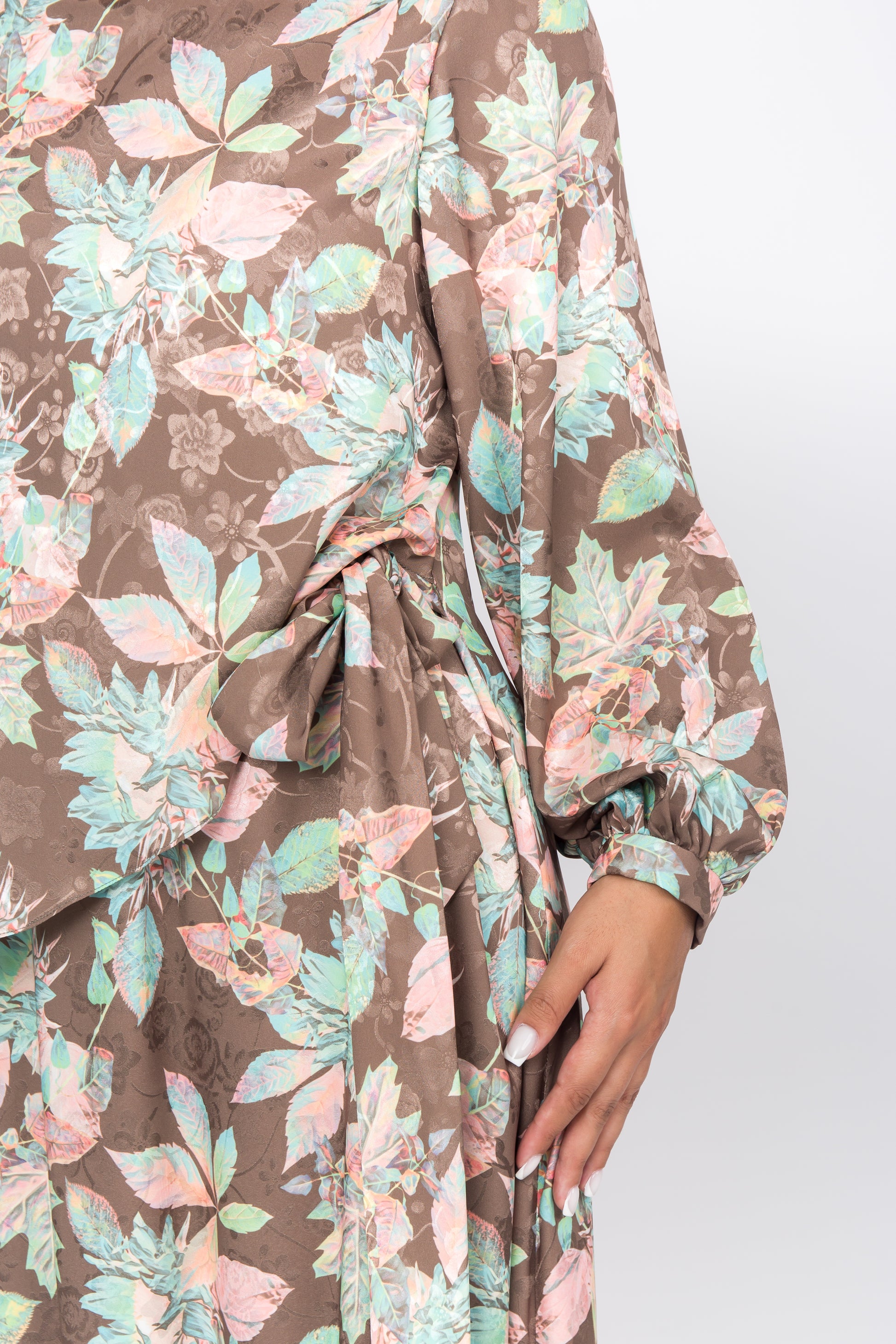 Close up of the dress featuring a colorful print, flattering overlay front panel, and comfortable puff sleeves tied at the side.