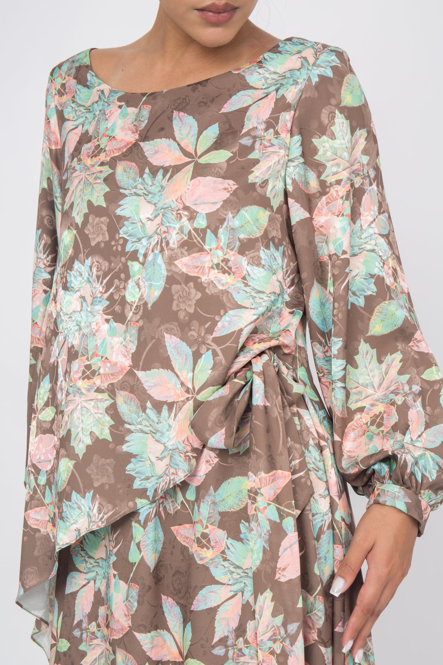 Close up of a dress which features a colorful print, flattering overlay front panel, and comfortable puff sleeves tied at the side.