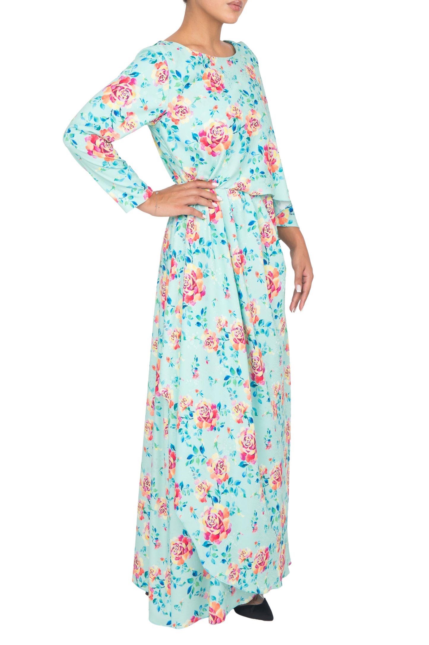 Side view of a model wearing aqua floral printed silk dress, posing against white background.