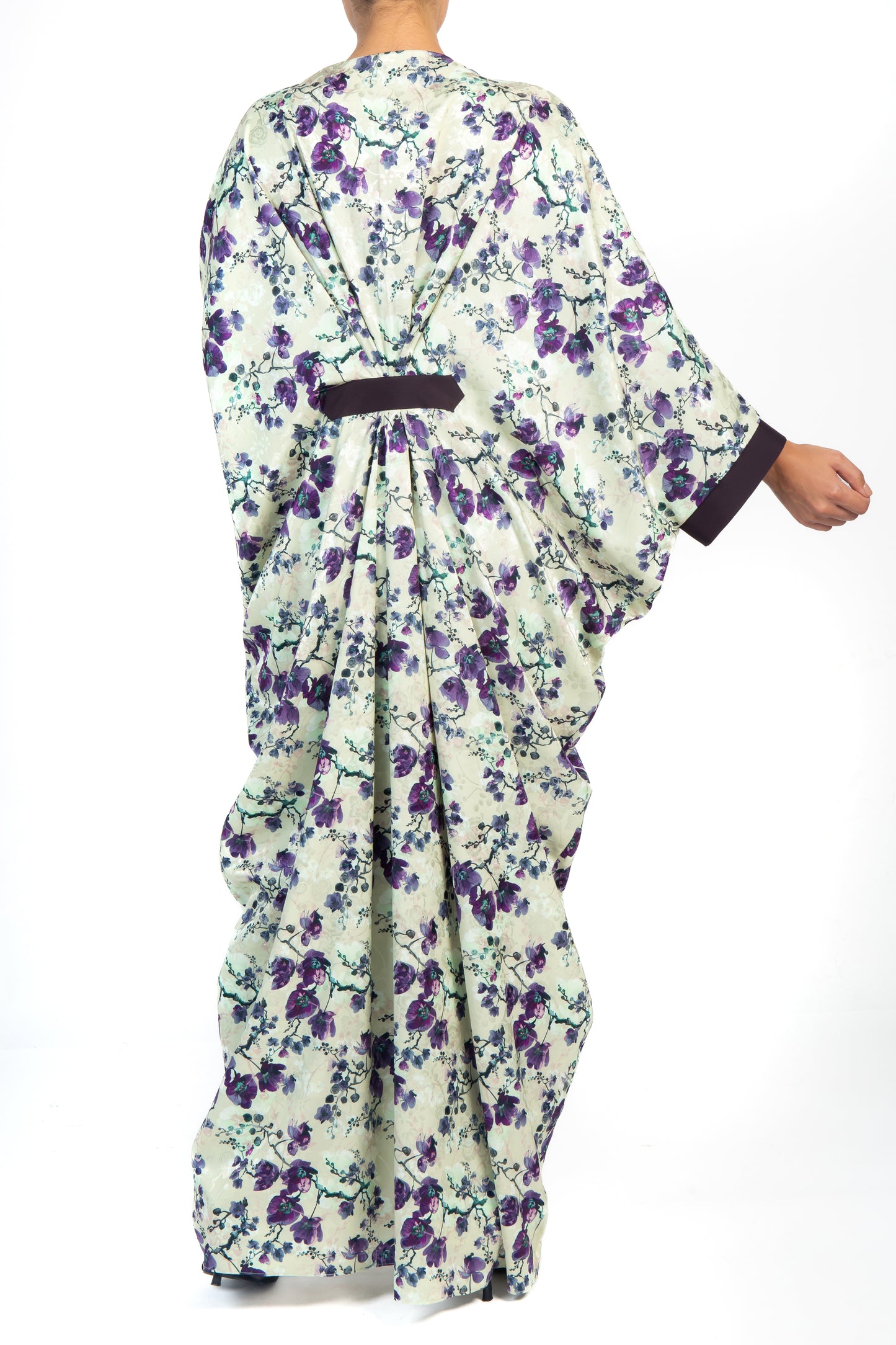 Back view of a woman wearing a floral kaftan that is purple, black and white