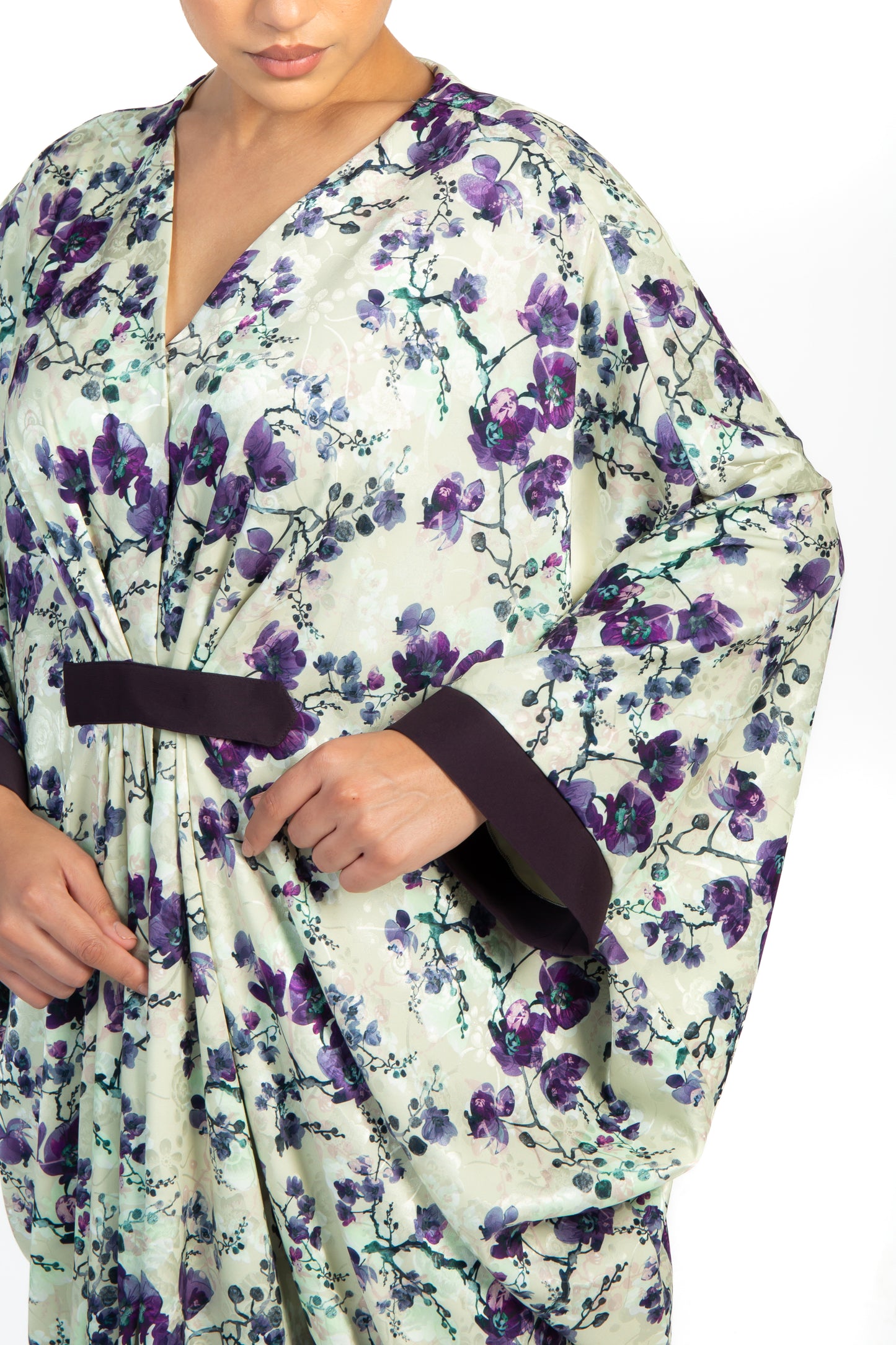 Side view of a woman wearing a floral kaftan that is purple, black and white